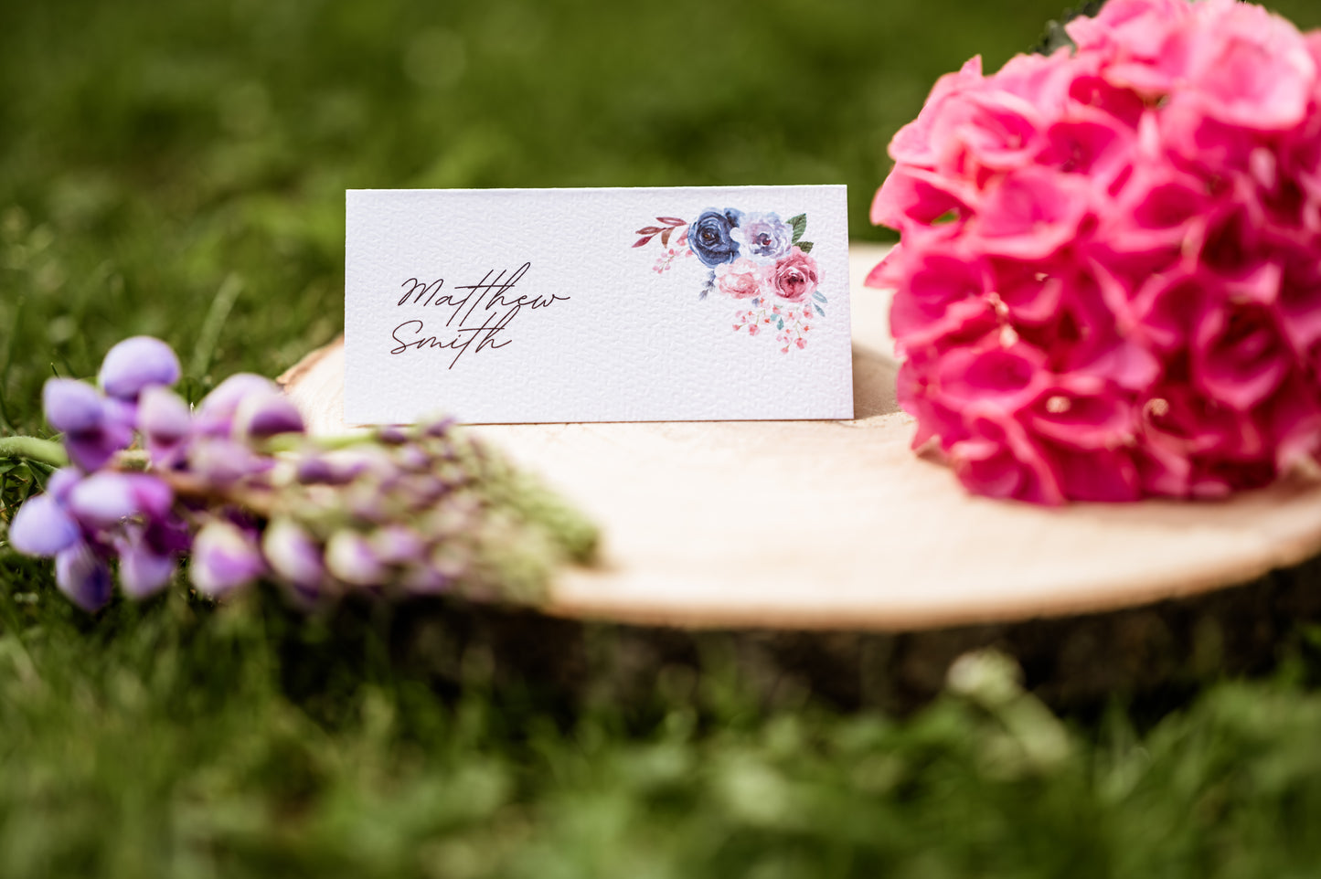 Place card with floral design on grass with pink flowers