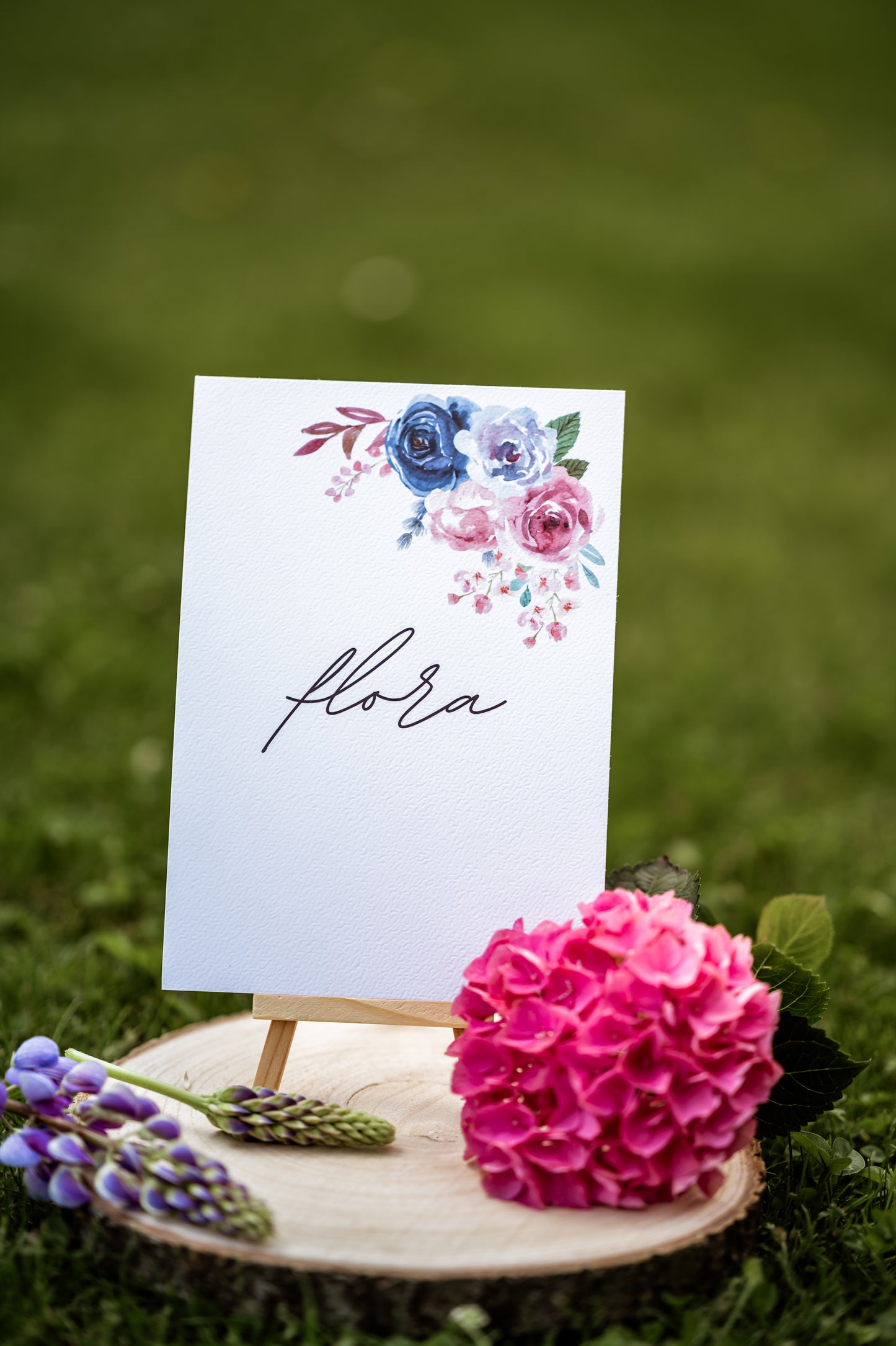Floral table name number sign displayed on a log slice with pink flowers